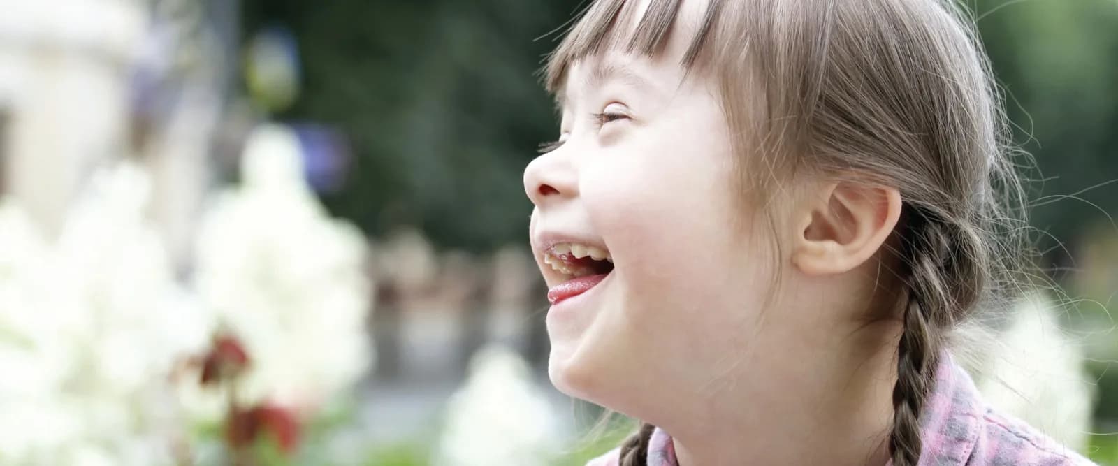 A laughing girl with Down syndrome with her hair in a braid