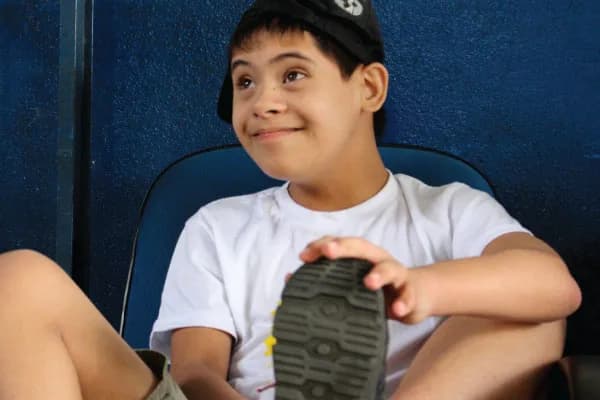 A smiling boy with Down syndrome sitting on a bench